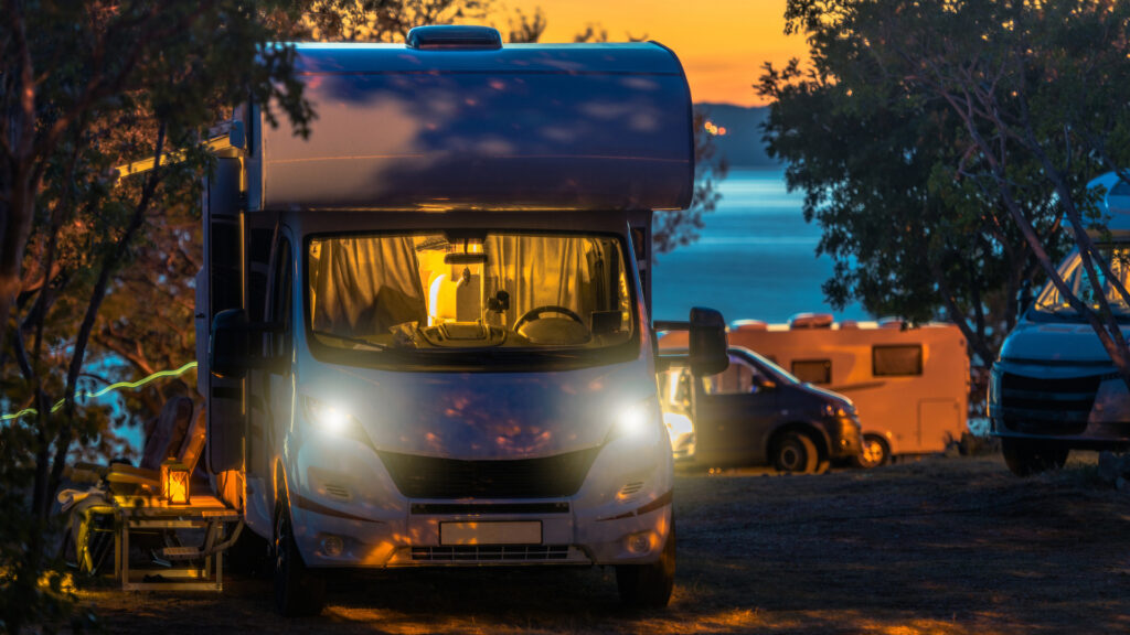 A camper van at a campsite with the lights on