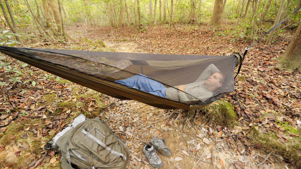 A man sleeping in a camping hammock