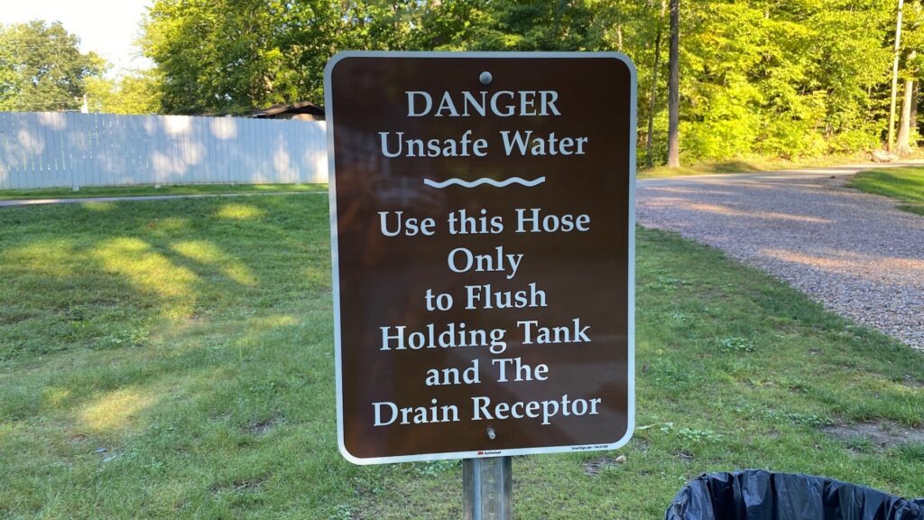 A sign at an RV park dump indicating to use only the hose for flushing the black tank. 